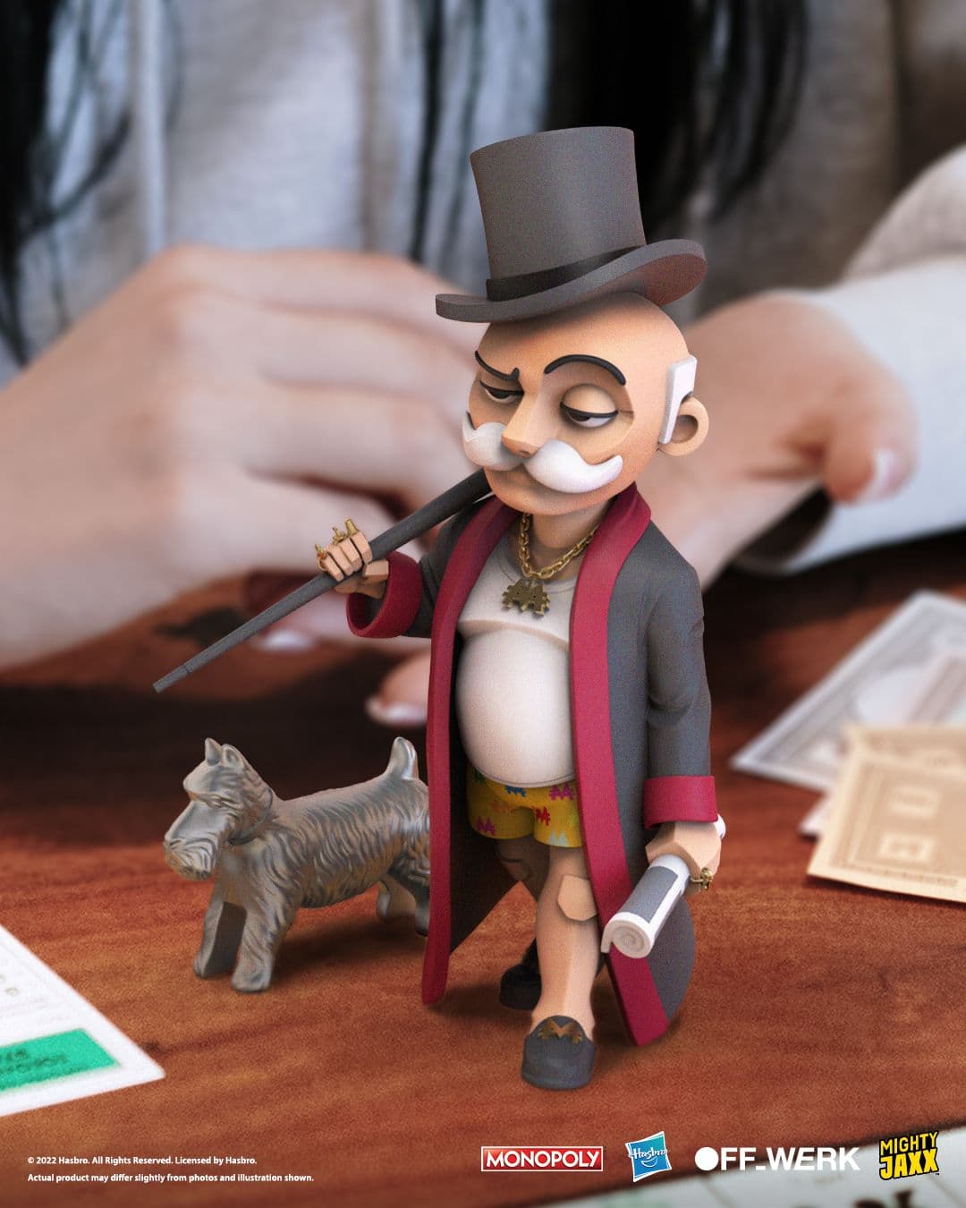 Mr. Monopoly in robe and shorts holding a cane and coffee beside his Scottie Dog, displayed on a tabletop setting.